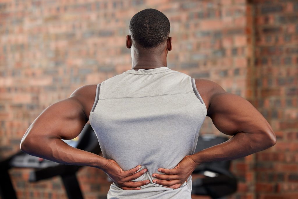 Back pain, fitness and exercise with a sports man suffering from an injury or inflammation during a